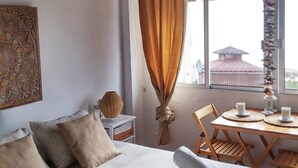A room with a bed, a table with two cups, a chair, and a window with curtains. - Bungalows Castillejos - Adults Only (Barbate)