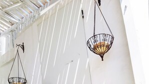 A white wall with two hanging lanterns and a door with a black handle. There are potted plants on the ground. - Bungalows Castillejos - Adults Only (Barbate)