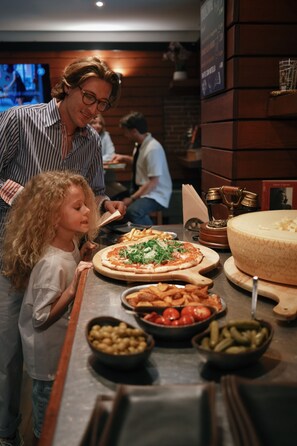 A restaurant interior with a pizza, olives, and pickles on the counter. - Suite & Breakfast 7 Vizi (Lazise)