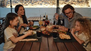 Un grupo de personas cenando en una mesa al aire libre, con diferentes platos y bebidas.