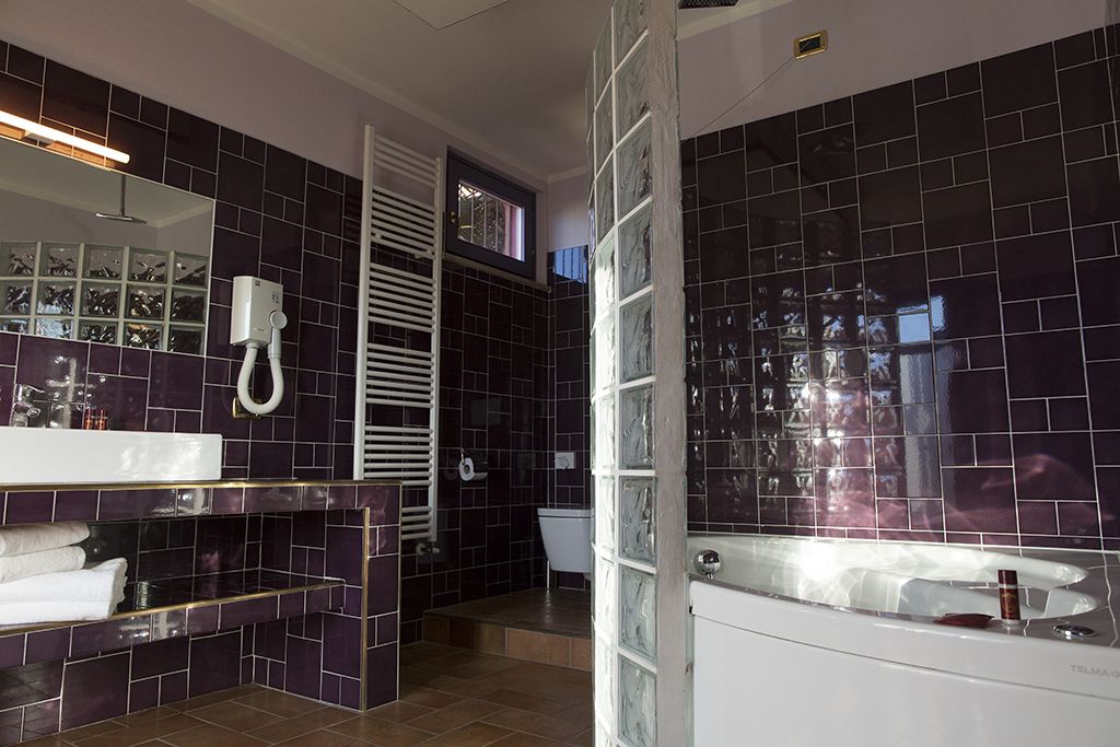 A modern bathroom with dark tiles, a white vanity, a glass shower enclosure, and a visible toilet.