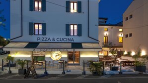 Un edificio con un letrero que dice 'PIZZA & CUCINA' y una zona de estar al aire libre.