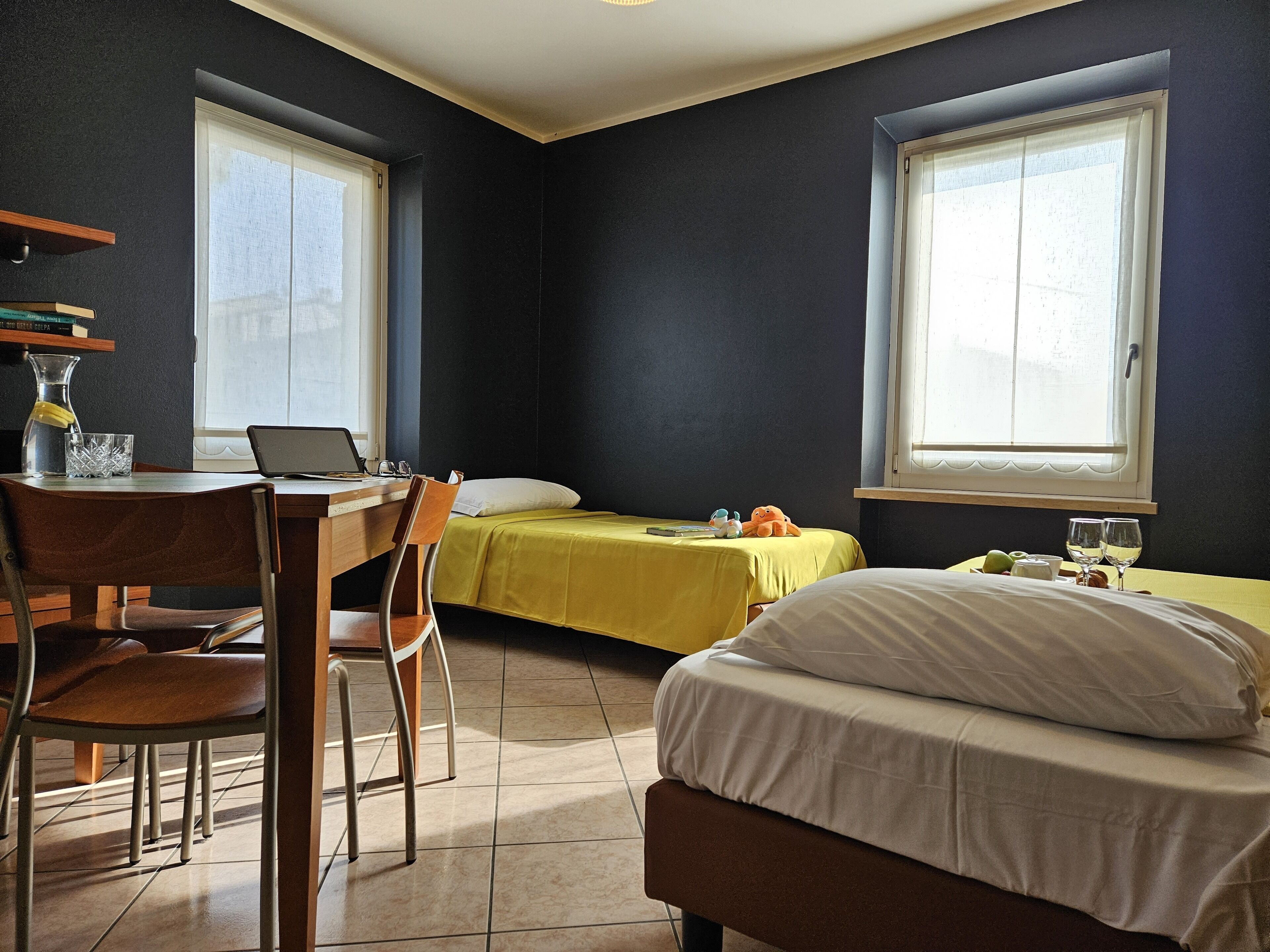 A compact hotel room with a bed, a desk with a laptop, a chair, and a window.