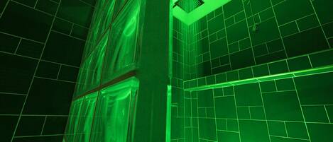A room with green-tinted walls and a tiled floor, featuring a large window and a vent on the ceiling.