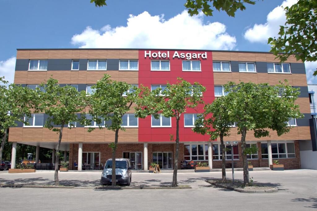 A multi-story hotel building with a red facade and a sign that reads 'Hotel Asgard.'