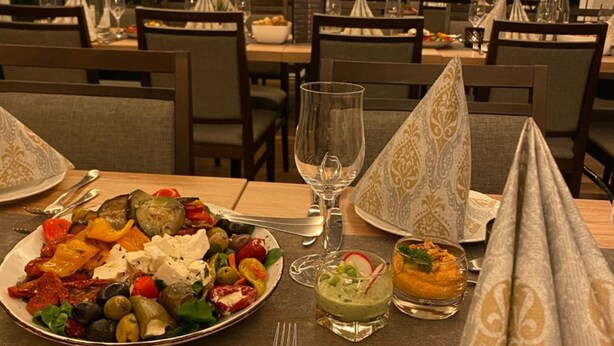 A restaurant dining area with tables set for meals, including plates of food and drinks. - Hotel Asgard (Gersthofen)