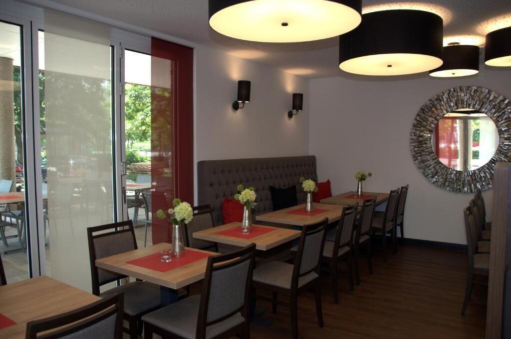 Un restaurante con varias mesas, sillas y un espejo grande en la pared.