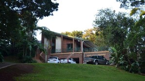 Un edificio de dos pisos con fachada de ladrillo, un balcón y una zona de estacionamiento techada.
