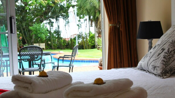 Habitación de hotel con cama, vista a una piscina y un patio con sillas y una mesa.