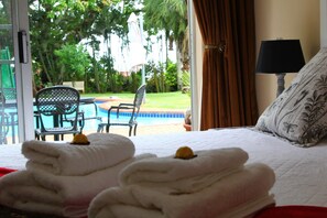 Habitación de hotel con cama, vista a una piscina y un patio con sillas y una mesa.