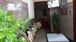 Un pasillo estrecho con un banco estampado, una mesita pequeña y plantas en macetas.