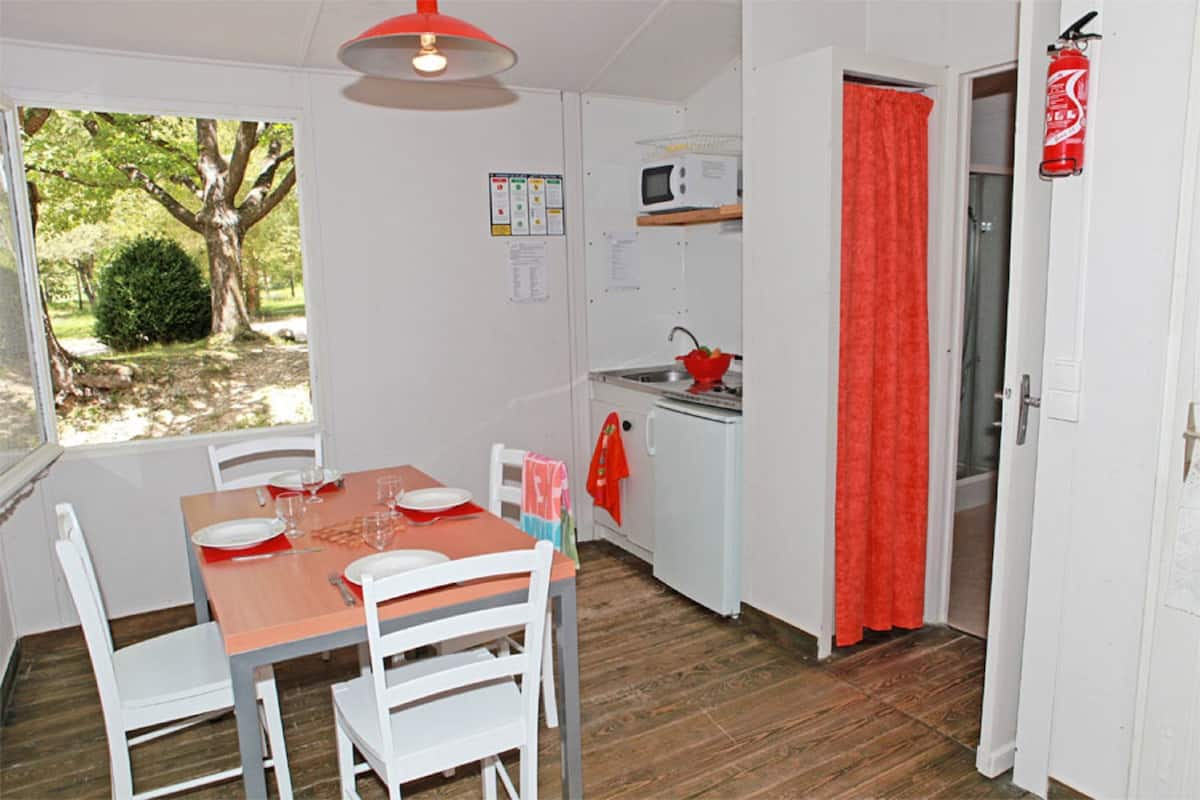 A compact kitchen with white cabinets, a microwave, and a red curtain.