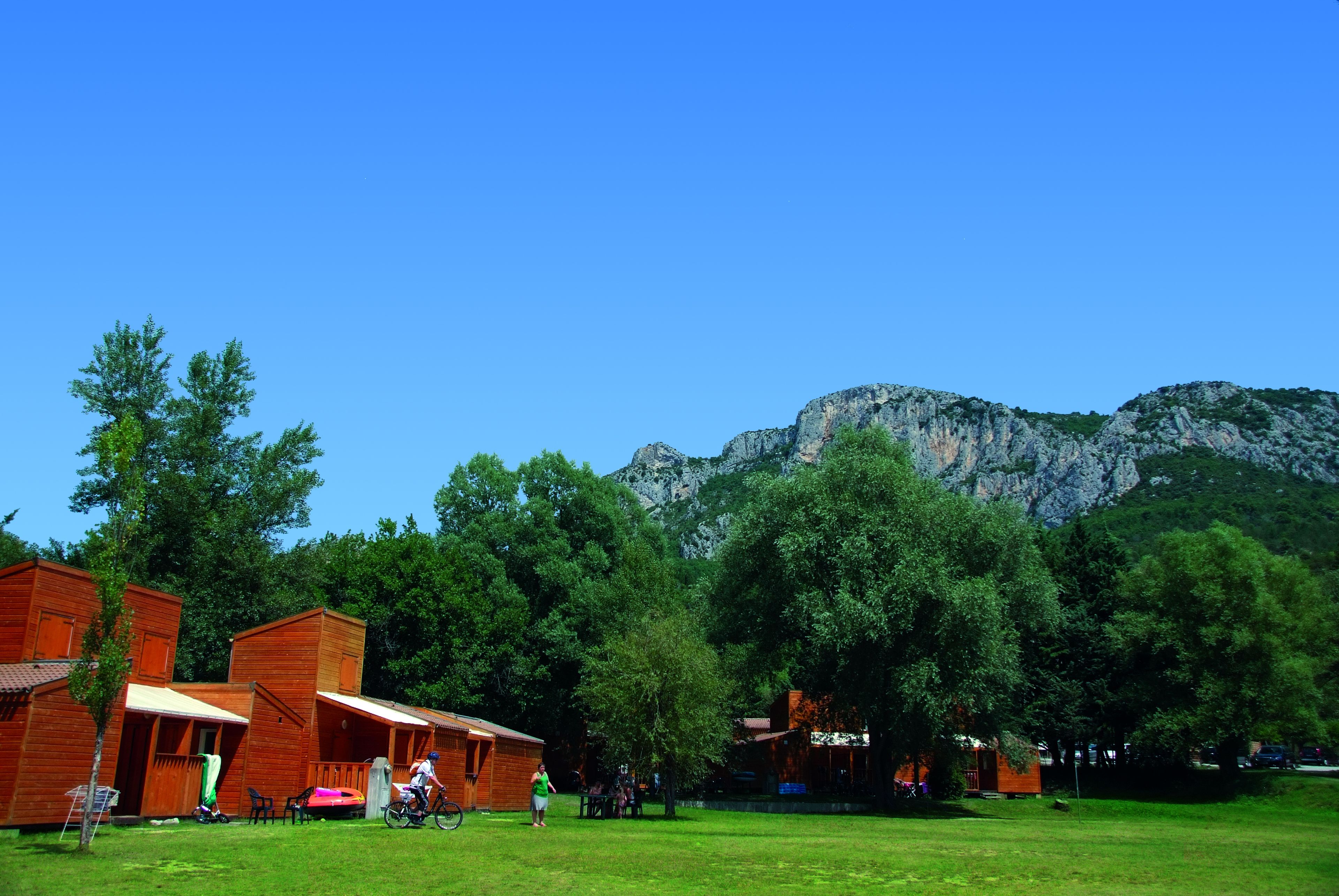Un chalet rustique avec des cabanes en bois, une cour verdoyante et une vue imprenable sur les montagnes.