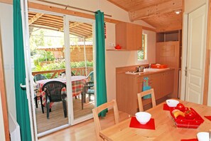 Un intérieur en bois avec une porte-fenêtre coulissante donnant sur un patio extérieur.