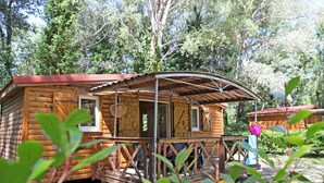 A wooden cabin with a porch and a metal roof, surrounded by trees. - Camping Domaine du Petit Lac (Moustiers-Sainte-Marie)