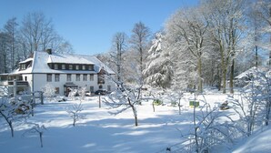A snow-covered hotel with a traditional European architectural style, a fenced garden, and a clear blue sky. - Hotel Wintersmühle (Bielefeld)