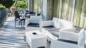A covered outdoor seating area with white wicker furniture, including sofas and chairs, and a small table with a book on it. - Hotel Sayonara (Cervia)