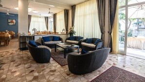 A spacious living area with a coffee table, sofas, and a dining area in the background. - Hotel Sayonara (Cervia)