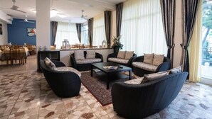 A spacious living area with a dining setup and a view of the outdoors. - Hotel Sayonara (Cervia)