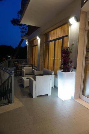 A balcony with outdoor seating and a potted plant. - Hotel Sayonara (Cervia)