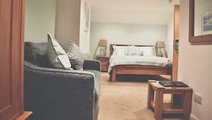 A bedroom with a bed, bedside tables, a chair, and a small table. - Count House Cottage B&B - Adults Only (St Ives)