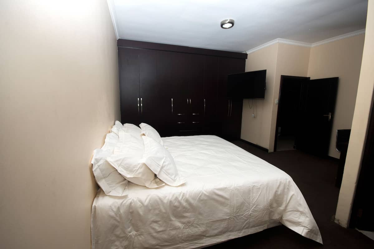 Hotellihuone, jossa on sänky, vaatekaappi ja televisio.