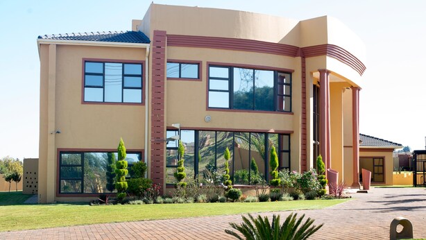 A modern two-story building with large windows, a brick pathway, and well-maintained landscaping. - 02 Phoka Trading (Pretoria)