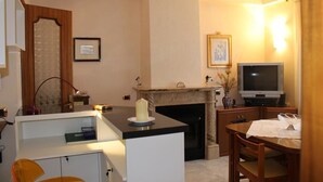 Uma sala de estar com lareira, televisão e um espaço de jantar com mesa e cadeiras.
