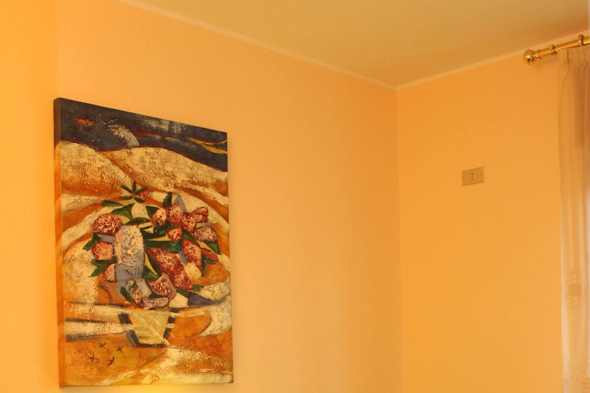 Un dormitorio con dos camas, ropa de cama colorida, un cuadro en la pared y una lámpara de noche.