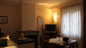 Uma sala de estar acolhedora, com lareira, televisão e área de refeições com mesa e cadeiras.