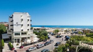 A hotel with a modern design, located near a beach with visible parking and a clear view of the sea. - Hotel Oriente (Cervia)