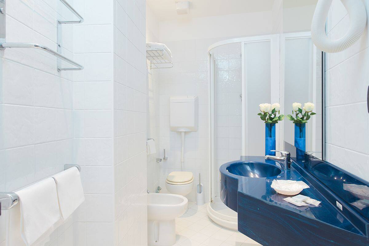 A modern bathroom with a glass shower enclosure, a white toilet, and a blue sink with a mirror.