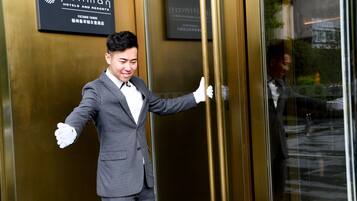 Un hombre con traje de pie frente a la entrada de un hotel, con un letrero que dice "pullman hotels and resorts".