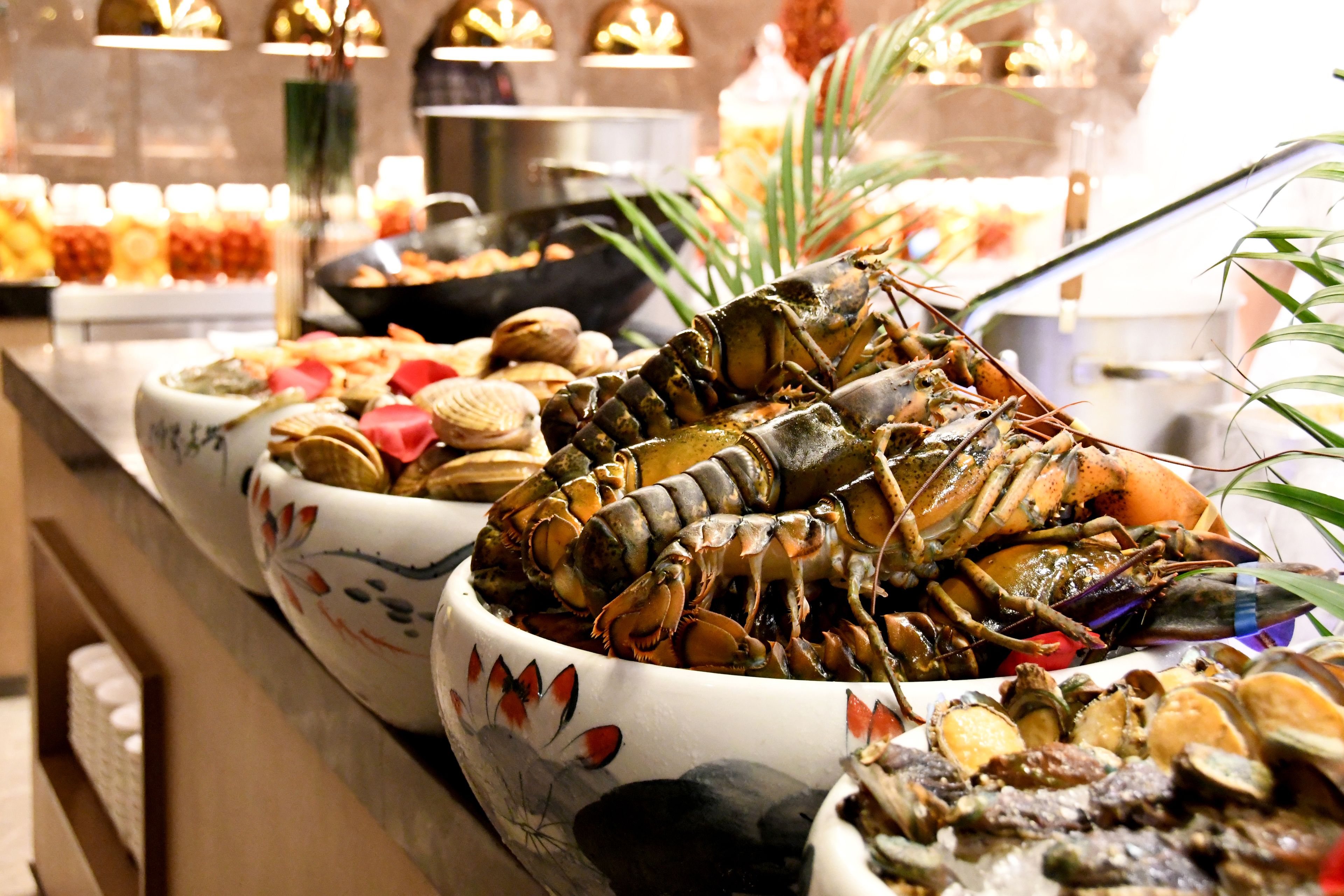 En buffet med forskellige fiskeanretninger, herunder hummer og østers, anrettet i dekorative skåle.