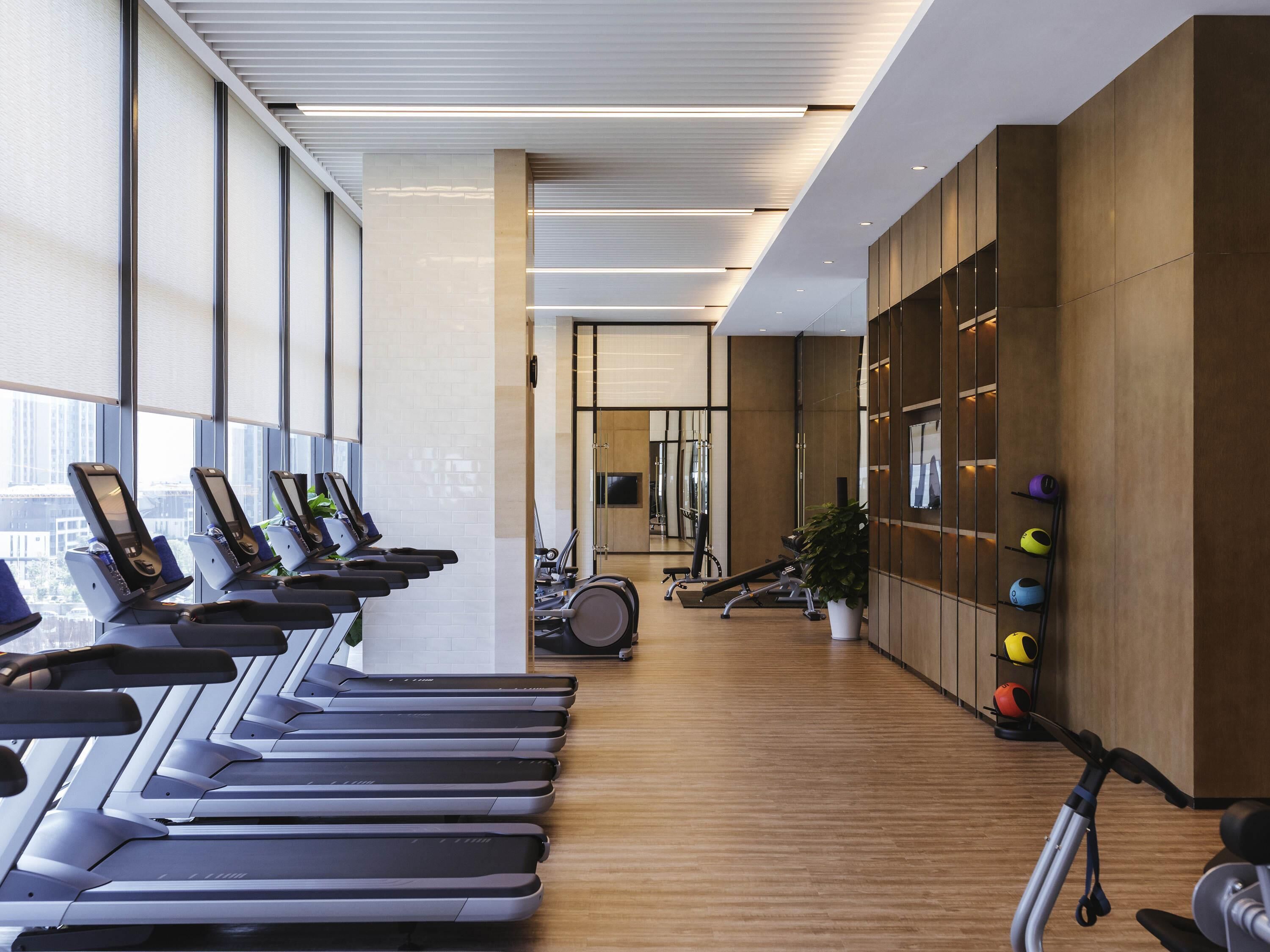 Une salle de sport équipée de tapis de course, de vélos d’exercice et de poids.