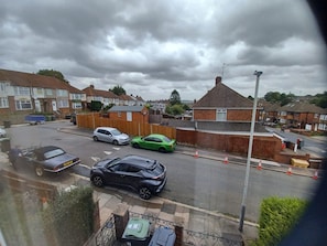 A residential street with houses, parked cars, and a visible trash bin. - Huku Kwetu - Milton House (Luton)