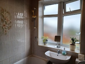 A bathroom with a large window, a sink, a mirror, and a shower. - Huku Kwetu - Milton House (Luton)