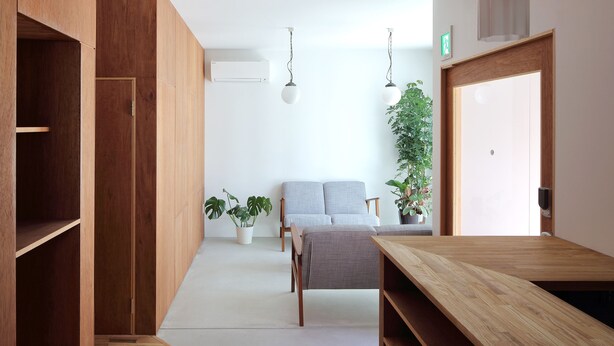 Una habitación moderna con muebles de madera, un sofá gris y plantas en macetas.