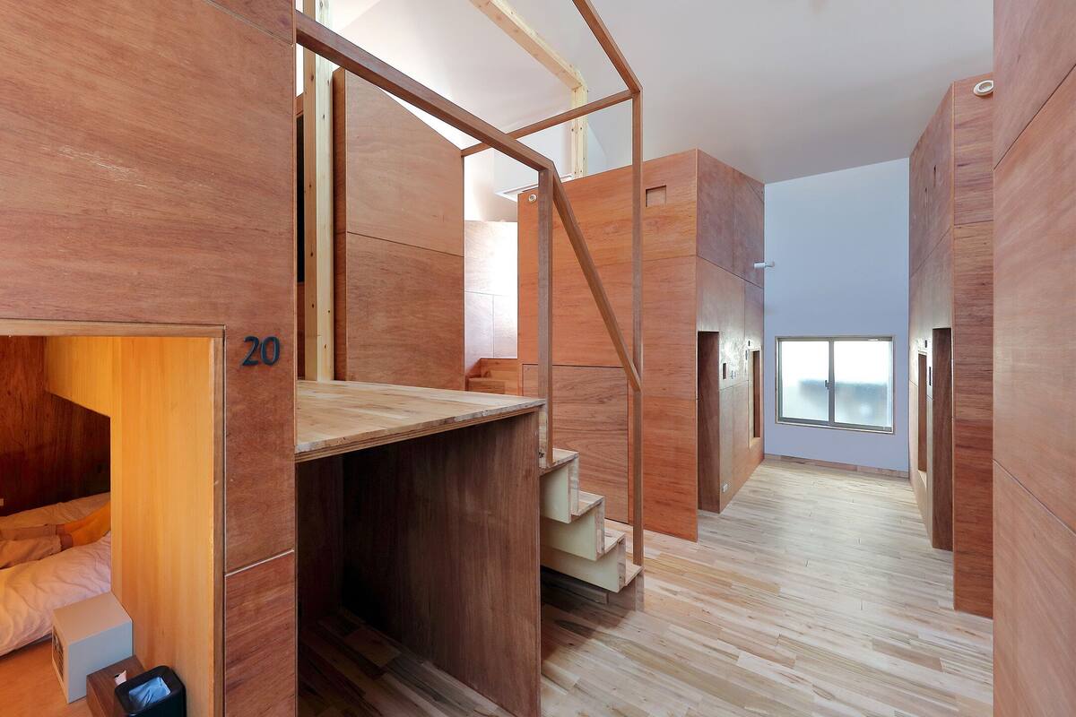 A modern interior with a loft-style bed, a staircase, and a large window providing natural light.