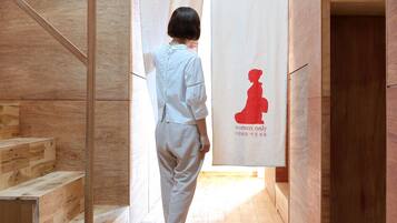 A person walking through a wooden interior space with a sign reading "women only" and a silhouette of a woman.
