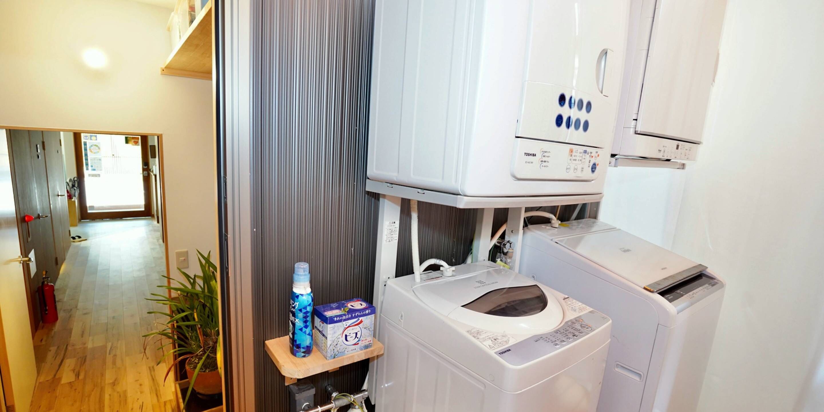 A compact laundry area with a washing machine, a dryer, and a shelf with a bottle and a box.