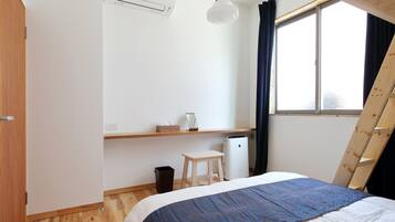 A bedroom with a bed, a desk, a chair, a heater, and a window with curtains.