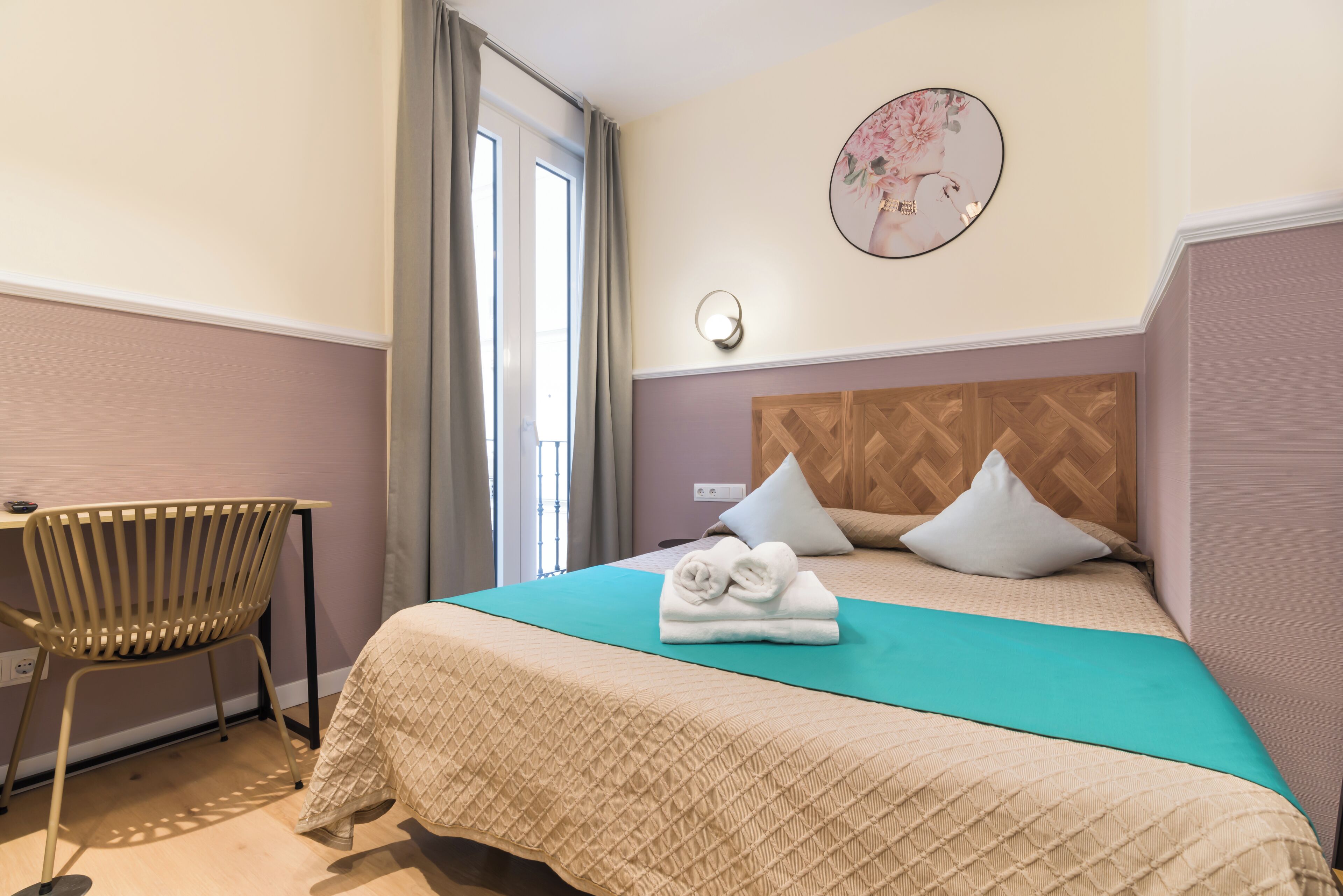 Habitación de hotel ordenada con una cama, un sillón y un reloj de pared.