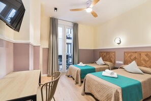 A hotel room with two beds, a TV, a ceiling fan, and a view of the outside balcony. - Hostal Evocare Madrid (Madrid)