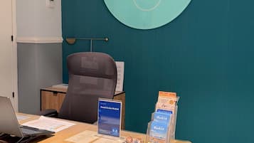 Een vergaderruimte met een tafel, stoelen, een laptop, een bordje voor Hostel Evolve Madrid, en een rond wandbord met de naam 'Evolve Madrid'.