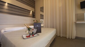 Una habitación de hotel con una cama bien hecha, una bandeja con una botella de champán, fresas y una copa de champán.