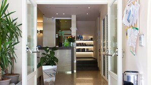 Un vestíbulo de hotel con una recepción, una estantería y una planta en maceta.