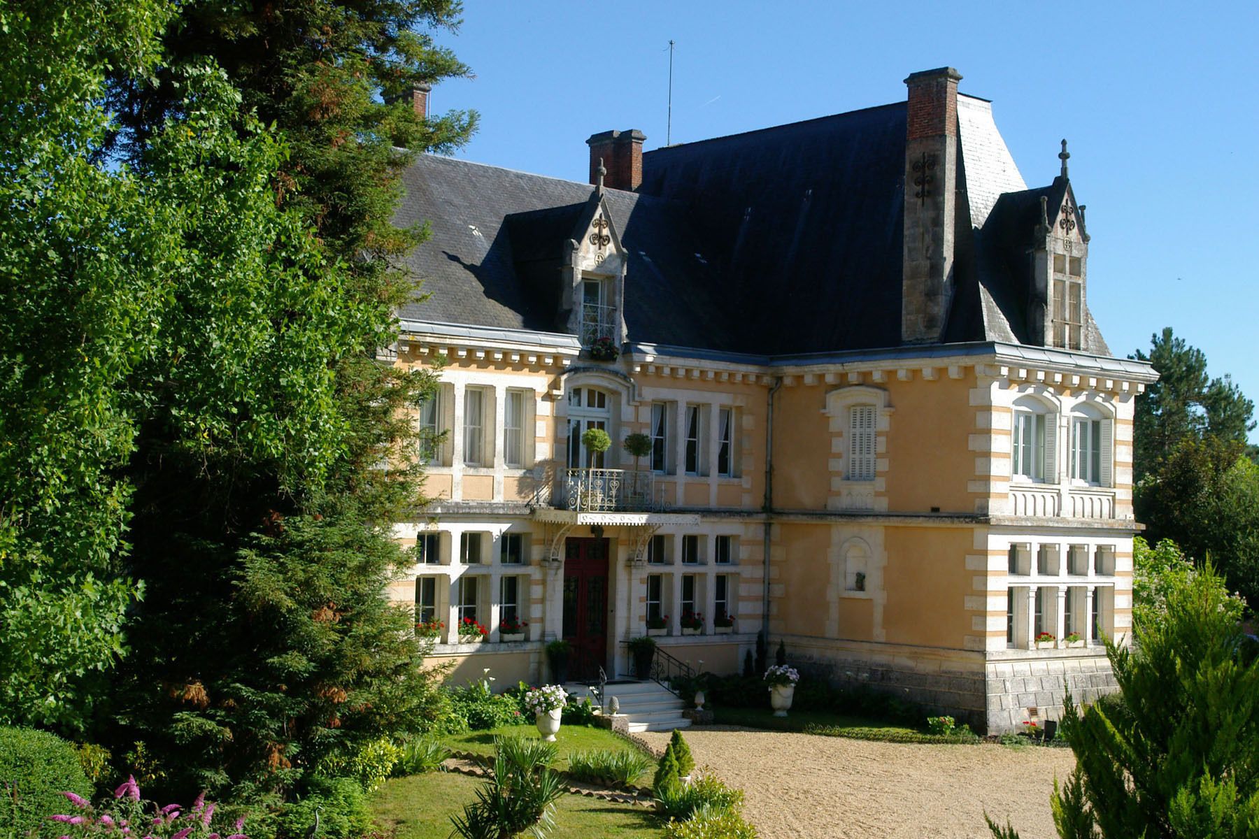 A large, historic building with multiple stories, a prominent entrance, and a well-maintained garden.