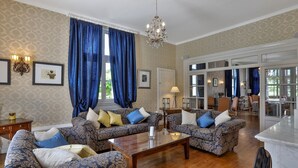 A spacious living room with patterned sofas, a wooden coffee table, and a chandelier. - Château de Villars (Villars)