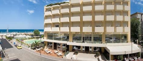 A hotel with multiple balconies, a pool area, and a view of the sea.